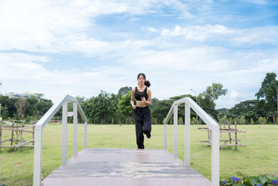 Full length of woman standing on railing against sky