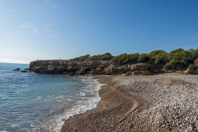 Rocks on beach against blue sky