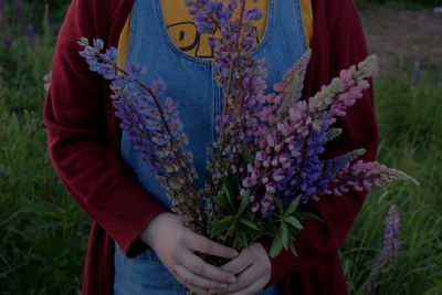 Midsection of woman holding purple flowering plants