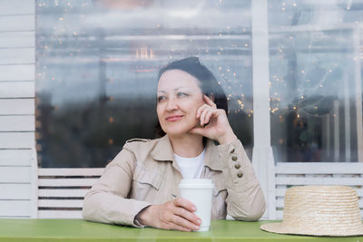 Portrait of a smiling young woman looking through window