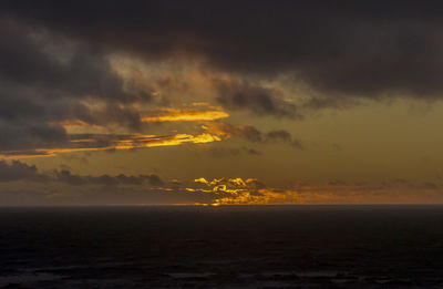 Scenic view of sea against dramatic sky during sunset