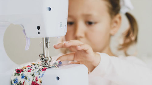 Close-up of cute girl using sewing machine