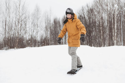 Cute teenage girl rides a snowskate in a winter park, healthy lifestyle