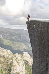 Hiker standing on edge of famous pulpit rock cliff, norway