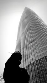 Low angle view of silhouette skyscraper against clear sky