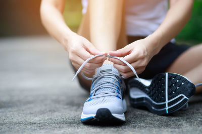 Low section of woman tying shoelace