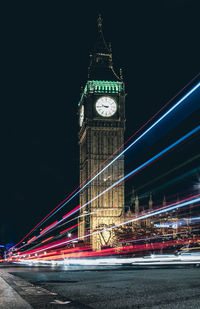 Low angle view of illuminated clock tower at night