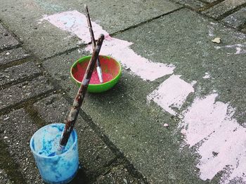 High angle view of powdered paints and brushes in bowls on street