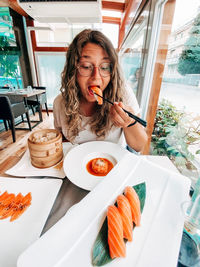 Young woman eating food at restaurant