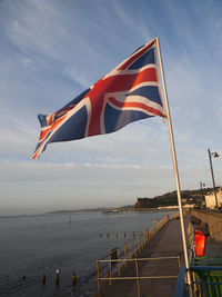 Scenic view of flag by sea against sky