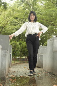 Portrait of a smiling young woman standing against trees