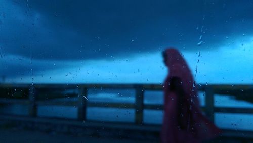 Woman seen through wet window in rainy season