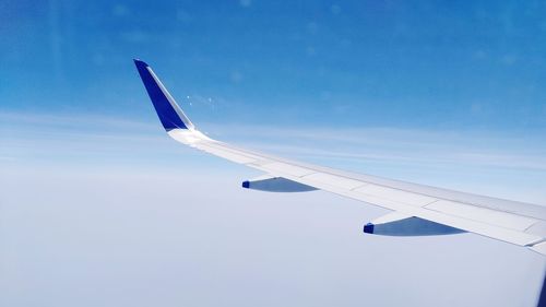 Cropped image of airplane wing against blue sky