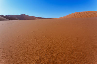 Sand dunes in desert against clear sky