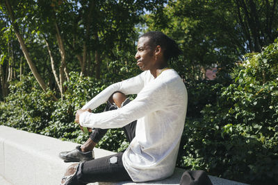 Man sitting on retaining wall at park