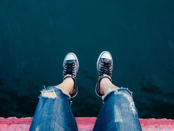 Low section of person standing against blue water