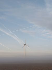 Wind turbines on field against sky