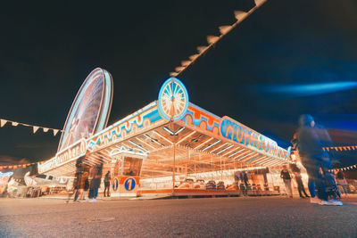 Illuminated ferris wheel against sky at night