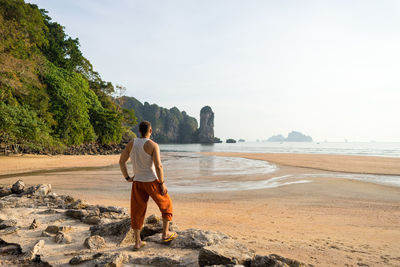 Rear view of ma looking at sea while standing on rock