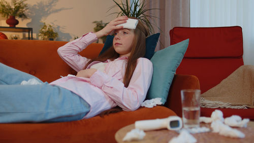 Young woman using mobile phone while lying on bed at home