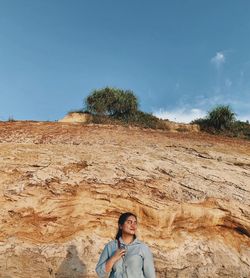 Smiling woman standing against rock