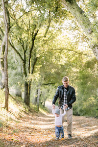 Toddler boy and young father walking on a hiking trail holding hands