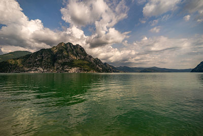 Scenic view of sea by mountains against sky