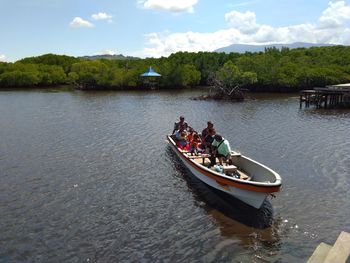 People in boat on lake against sky