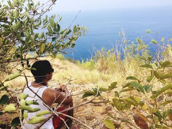 Man sitting on hill by sea