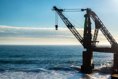 Crane over sea against sky