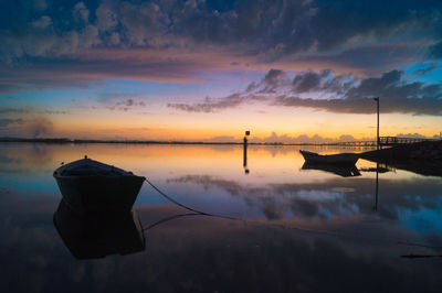 Boats moored on sea against sky during sunset