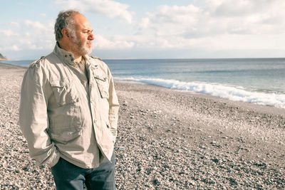 Happy middle-aged bearded man walking along deserted winter beach.