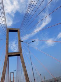 Low angle view of suspension bridge against cloudy sky