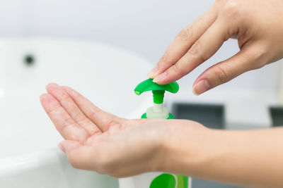 Cropped hand pressing soap dispenser in bathroom