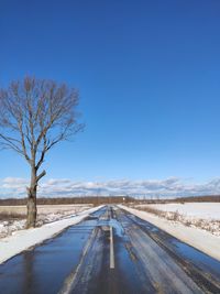 Road amidst snow covered landscape against sky