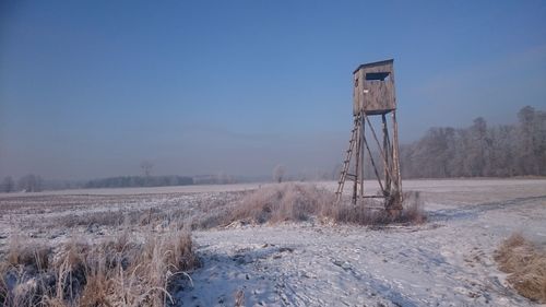 Lookout tower on snowy field against sky
