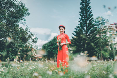 Portrait of woman standing by plants against trees