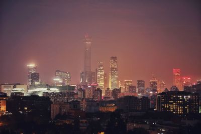 Illuminated buildings in city against sky at night