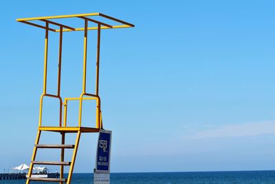 Lifeguard hut against sea against clear blue sky