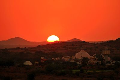 Scenic view of landscape and mountains against orange sky