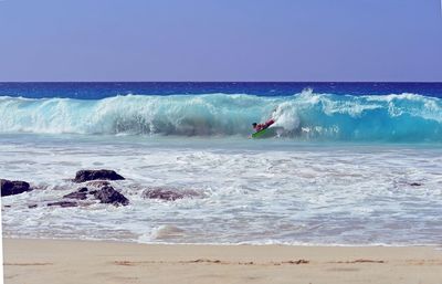 Young man surfing on sea against clear sky