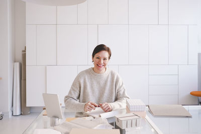 Portrait of smiling mature entrepreneur sitting at desk in upholstery store