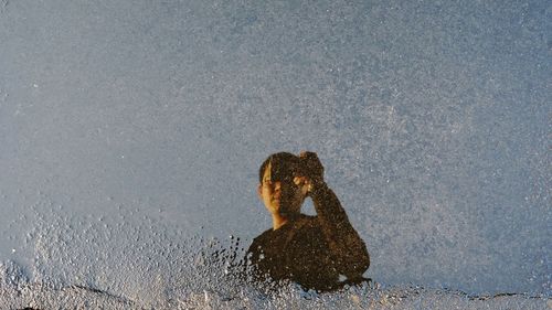 Man photographing while reflection in water