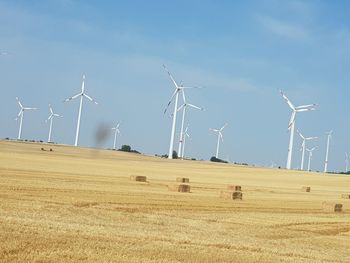 Windmills on field against sky