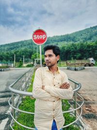 An indian young man standing at the traffic chowk in front of stop signal. 