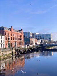 Buildings by river against sky