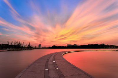 Road in city against sky at sunset