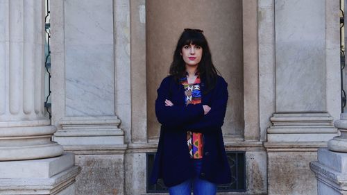 Portrait of a young woman standing against building