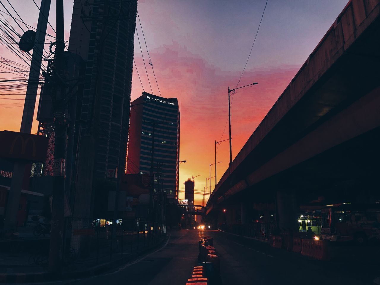 ROAD BY BUILDINGS AGAINST SKY AT SUNSET