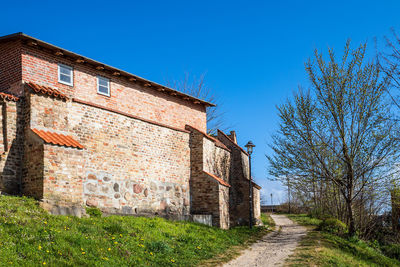 Road amidst buildings against clear blue sky